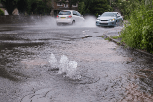 Flooded streets, blocked drains and two vehicles moving past