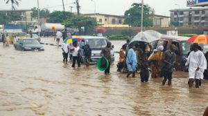 Vehicles and people moving in knee-level floodwater